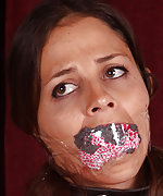 Latex beauty chained, mouth-stuffed, tape-gagged